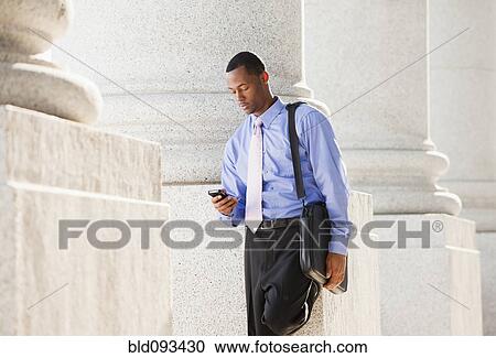 Black businessman text messaging on cell phone outdoors View Large Photo Image Stock Image - Black businessman text messaging on cell phone outdoors. Fotosearch