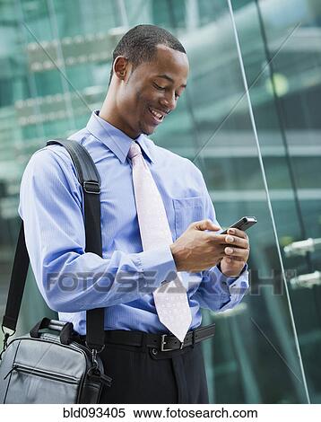 Black businessman text messaging on cell phone View Large Photo Image Stock Photography - Black businessman text messaging on cell phone. Fotosearch