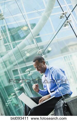 Stock Image - Black businessman using laptop outdoors. Fotosearch