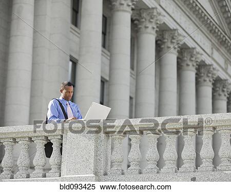 Stock Photography - Black businessman using laptop outdoors. Fotosearch