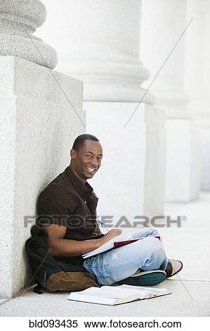 Stock Photography - Black college student doing homework outdoor. Fotosearch