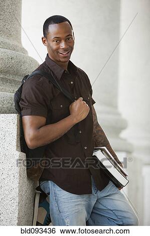 Stock Photograph - Black college student holding books outdoors. Fotosearch