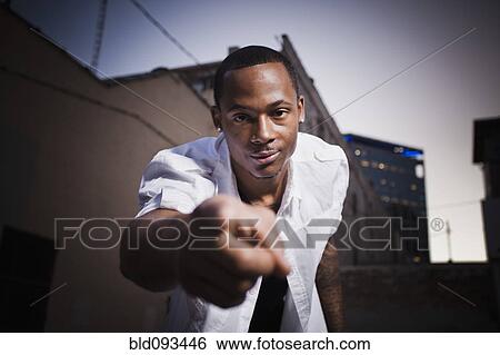Stock Photograph - Black man standing outdoors pointing. Fotosearch