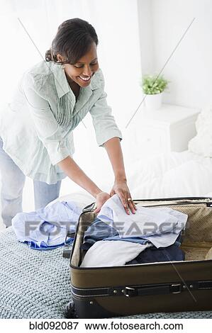 Black woman packing suitcase View Large Photo Image Stock Photo - Black woman packing suitcase. Fotosearch