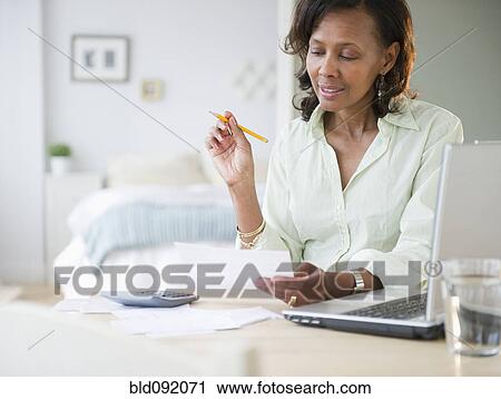 Stock Image - Black woman paying bills. Fotosearch