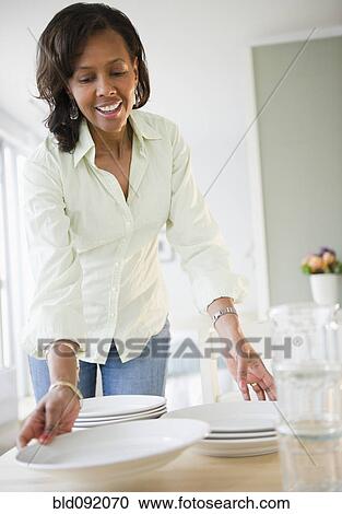Stock Image - Black woman setting table. Fotosearch