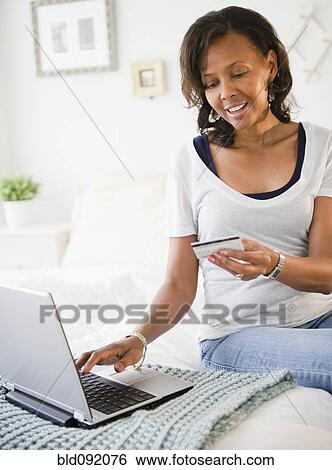 Stock Photograph - Black woman shopping online with credit card. Fotosearch