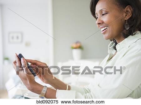 Stock Photography - Black woman text messaging on cell phone. Fotosearch