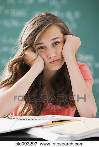 Stock Photo - Bored Caucasian teenager studying on classroom. Fotosearch