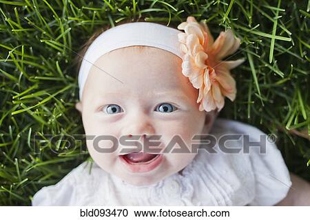 Stock Image - Caucasian baby girl laying in grass. Fotosearch