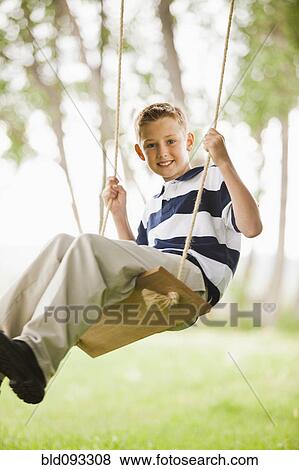 Stock Photo - Caucasian boy swinging on swing. Fotosearch