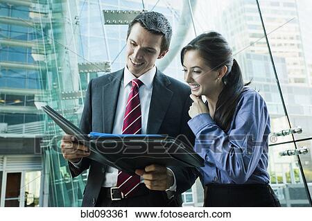 Stock Image - Caucasian business people looking at notebook together. Fotosearch