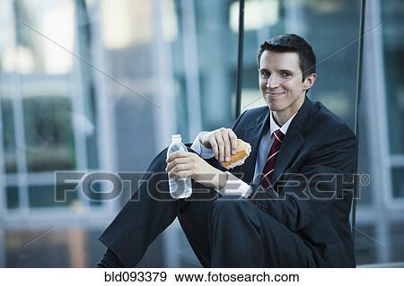 Stock Photo - Caucasian businessman eating lunch. Fotosearch