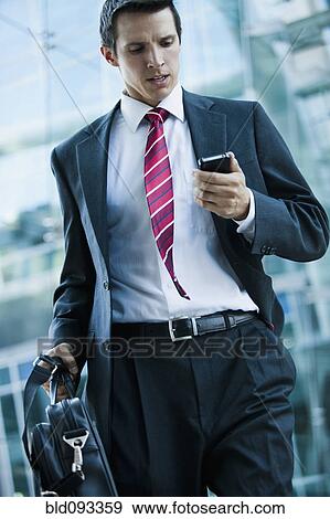 Caucasian businessman looking at cell phone outdoors View Large Photo Image Stock Photo - Caucasian businessman looking at cell phone outdoors. Fotosearch