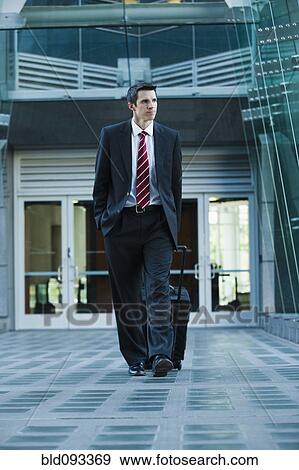 Caucasian businessman pulling suitcase outdoors View Large Photo Image Stock Photo - Caucasian businessman pulling suitcase outdoors. Fotosearch