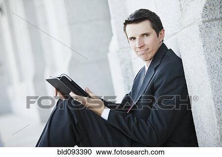 Stock Image - Caucasian businessman using digital tablet outdoors. Fotosearch