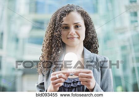 Stock Photography - Caucasian businesswoman holding glowing light bulb. Fotosearch