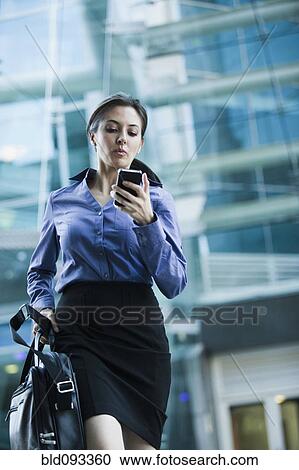 Caucasian businesswoman looking at cell phone outdoors View Large Photo Image Stock Image - Caucasian businesswoman looking at cell phone outdoors. Fotosearch