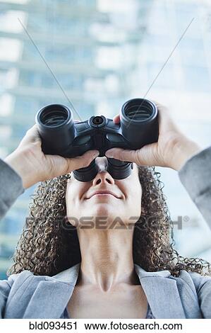 Stock Image - Caucasian businesswoman looking through binoculars. Fotosearch