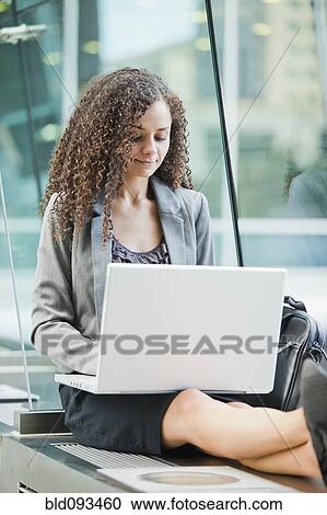 Stock Image - Caucasian businesswoman using laptop outdoors. Fotosearch