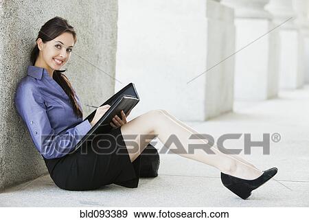 Stock Photo - Caucasian businesswoman writing in notebook outdoors. Fotosearch