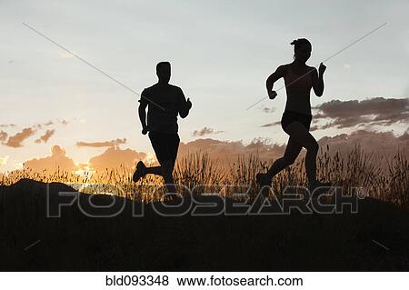 Stock Photo - Caucasian couple running together at sunset. Fotosearch