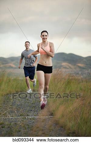 Picture - Caucasian couple running together on remote path. Fotosearch