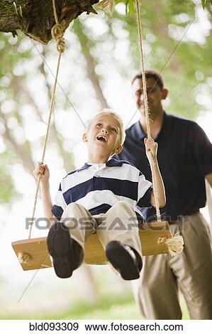 Caucasian father pushing son on swing View Large Photo Image Stock Photo - Caucasian father pushing son on swing. Fotosearch