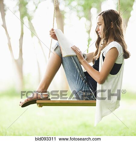 Caucasian girl reading book on swing View Large Photo Image Stock Image - Caucasian girl reading book on swing. Fotosearch