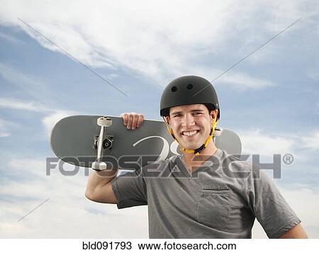 Stock Image - Caucasian man holding skateboard. Fotosearch