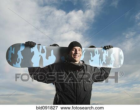 Stock Photo - Caucasian man holding snowboard. Fotosearch