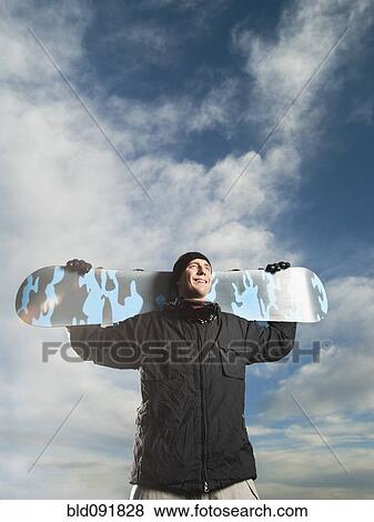 Stock Photo - Caucasian man holding snowboard. Fotosearch