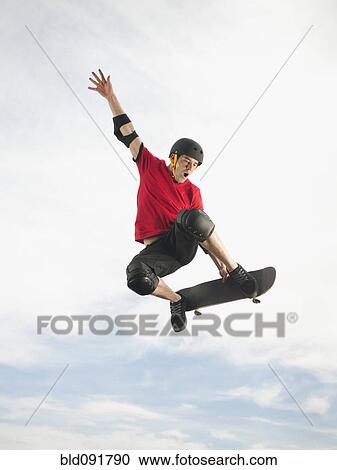 Caucasian man on skateboard in mid-air View Large Photo Image Stock Image - Caucasian man on skateboard in mid-air. Fotosearch
