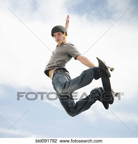 Stock Image - Caucasian man on skateboard in mid-air. Fotosearch