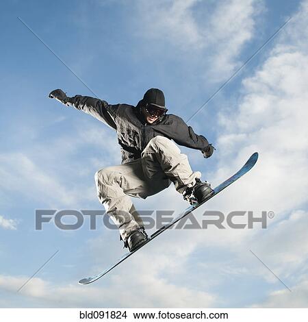 Picture - Caucasian man on snowboard in mid-air. Fotosearch