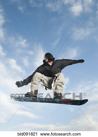 Stock Image - Caucasian man on snowboard in mid-air. Fotosearch