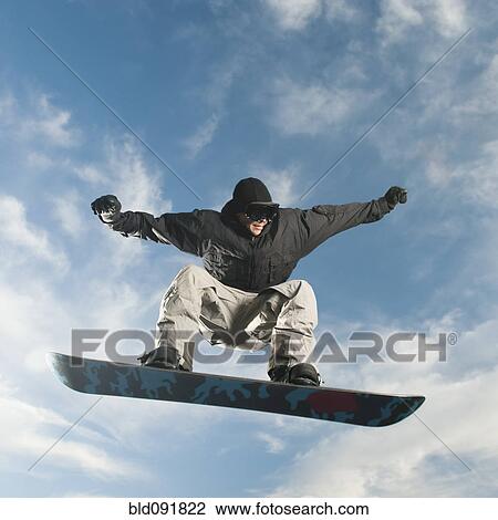 Stock Image - Caucasian man on snowboard in mid-air. Fotosearch