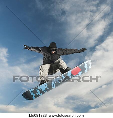 Stock Image - Caucasian man on snowboard in mid-air. Fotosearch