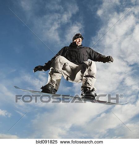 Caucasian man on snowboard in mid-air View Large Photo Image Stock Photography - Caucasian man on snowboard in mid-air. Fotosearch