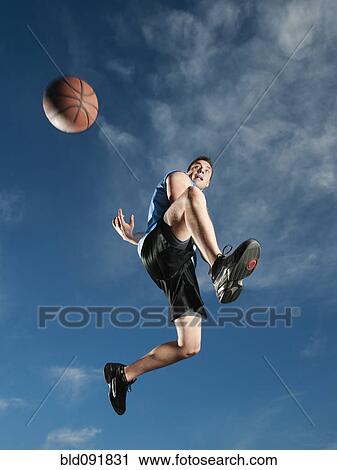 Stock Image - Caucasian man playing basketball. Fotosearch