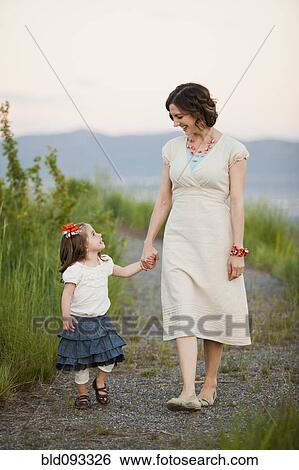 Stock Photograph - Caucasian mother and daughter walking on path. Fotosearch