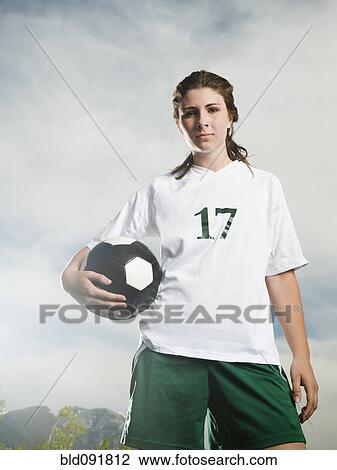 Stock Image - Caucasian soccer player holding ball. Fotosearch