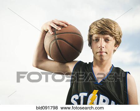 Stock Photo - Caucasian teenager holding basketball. Fotosearch