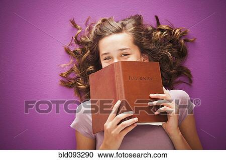 Stock Image - Caucasian teenager holding journal. Fotosearch