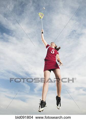 Picture - Caucasian teenager in mid-air playing lacrosse. Fotosearch