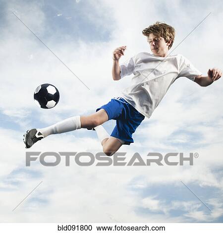 Caucasian teenager kicking soccer ball in mid-air View Large Photo Image Stock Image - Caucasian teenager kicking soccer ball in mid-air. Fotosearch