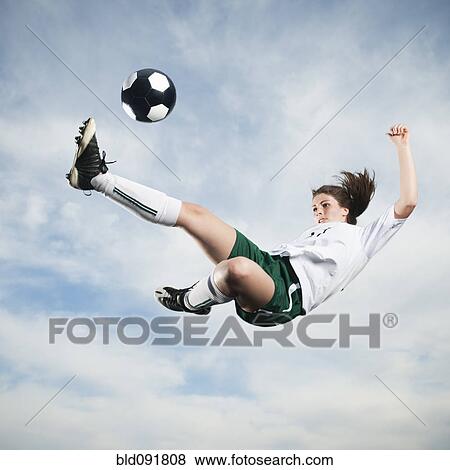 Stock Photo - Caucasian teenager kicking soccer ball in mid-air. Fotosearch