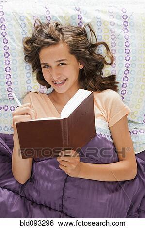 Caucasian teenager laying in bed writing in journal View Large Photo Image Stock Photograph - Caucasian teenager laying in bed writing in journal. Fotosearch