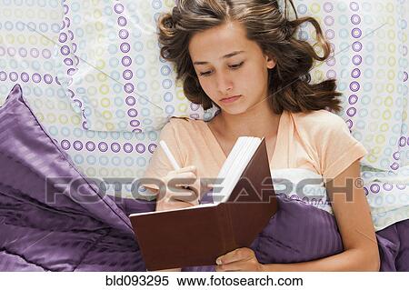 Caucasian teenager laying in bed writing in journal View Large Photo Image Stock Photography - Caucasian teenager laying in bed writing in journal. Fotosearch