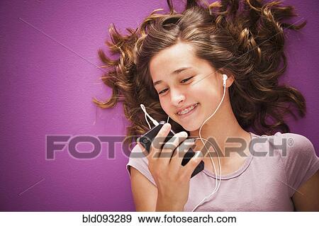 Stock Photo - Caucasian teenager listening to music on mp3 player. Fotosearch